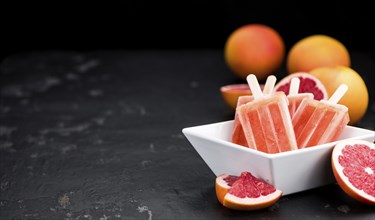 Some freshly made Grapefruit Popsicles (with some fresh fruits, selective focus)
