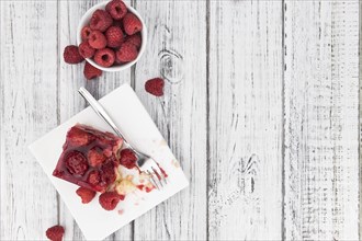 Piece of Raspberry Cake on an old wooden table (selective focus, close-up shot)