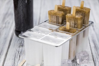 Some homemade Cola Popsicles (close-up shot, selective focus) on vintage background