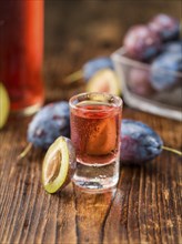 Homemade Plum Liqueur on an wooden table as detailed close-up shot, selective focus