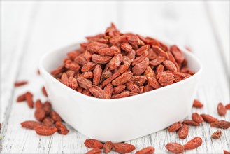 Dried Goji Berries as high detailed close-up shot on a vintage wooden table (selective focus)