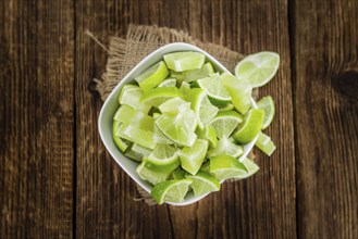 Sliced Limes on an old wooden table as detailed close-up shot (selective focus)