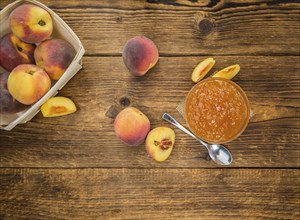 Peach Jam on an old wooden table as detailed close-up shot, selective focus