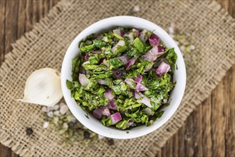 Healthy homemade Chimichurri on a wooden table as detailed close-up shot (selective focus)