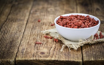 Dried Goji Berries as high detailed close-up shot on a vintage wooden table (selective focus)