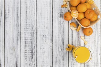 Wooden table with fresh homemade Tangerine Juice (close-up shot, selective focus)