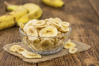 Homemade Dried Banana Chips on an wooden table as detailed close-up shot, selective focus