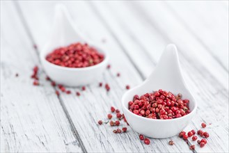 Pink Peppercorns as high detailed close-up shot on a vintage wooden table, selective focus