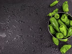 Portion of Raw Pimientos as detailed close up shot on a slate slab, selective focus