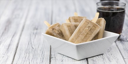 Fresh made Cola Popsicles on wooden background (selective focus, close-up shot)