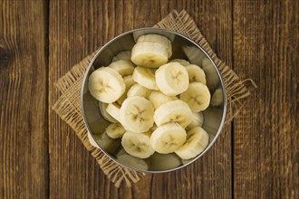 Sliced Bananas as high detailed close-up shot on a vintage wooden table, selective focus