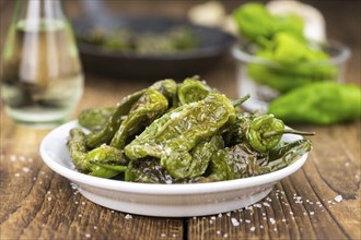 Pimientos de Padron on rustic wooden background as close-up shot