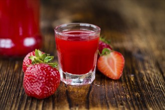 Homemade Strawberry liqueur on an wooden table as detailed close-up shot, selective focus