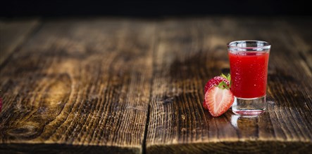 Homemade Strawberry liqueur on an wooden table as detailed close-up shot, selective focus