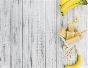 Banana Popsicles (on wooden background) as detailed close-up shot