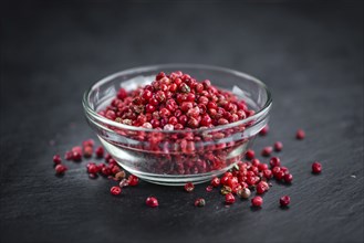 Portion of Pink Peppercorns on a rustic slate slab, selective focus, close-up shot
