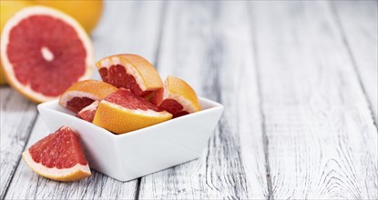Portion of sliced Grapefruits on an old wooden table (selective focus, close-up shot)