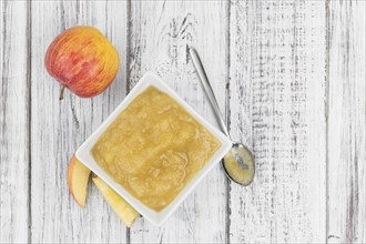 Homemade Applesauce (selective focus, close-up shot) on vintage background with some fresh fruits