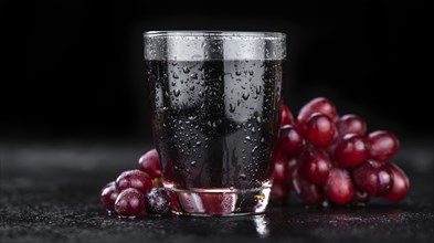 Portion of healthy Red Grape Juice on a slate slab (selective focus)