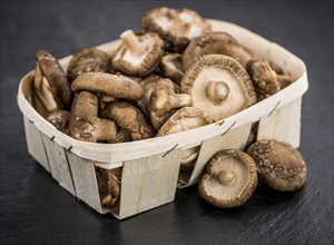 Portion of Raw Shiitake mushrooms on a rustic slate slab, selective focus, close-up shot