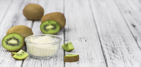 Bowl with fresh made Kiwi powder (close-up shot, selective focus) on an old wooden table