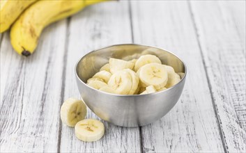 Sliced Bananas as high detailed close-up shot on a vintage wooden table, selective focus