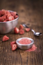 Strawberry powder as high detailed close-up shot on a vintage wooden table, selective focus