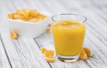 Homemade Tangerine Juice on an old and rustic wooden table (selective focus, close-up shot)