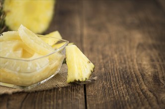 Preserved Pineapple Rings as high detailed close-up shot on a vintage wooden table, selective focus