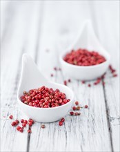 Pink Peppercorns on an old wooden table as detailed close-up shot, selective focus