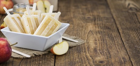 Vintage wooden table with Apple Popsicles (close-up shot, selective focus)