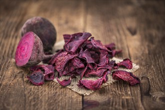 Vintage wooden table with Beetroot Chips (selective focus, close-up shot)