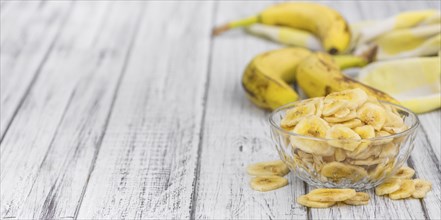 Homemade Dried Banana Chips on an wooden table as detailed close-up shot, selective focus