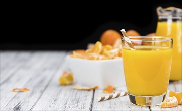 Homemade Tangerine Juice (close-up shot, selective focus) on a rustic background