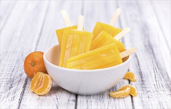 Portion of fresh homemade Tangerine Popsicles (close-up shot, selective focus) on a vintage