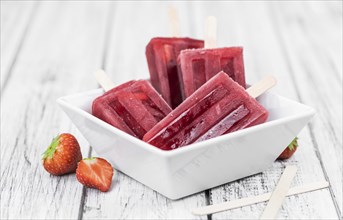 Homemade Strawberry Popsicles (close-up shot, selective focus) on vintage background