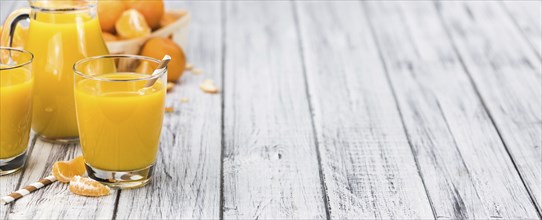 Homemade Tangerine Juice on an old and rustic wooden table (selective focus, close-up shot)