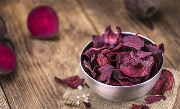 Vintage wooden table with Beetroot Chips (selective focus, close-up shot)