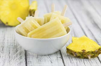 Old and rustic wooden table with homemade Pineapple Pipsicles (selective focus, close-up shot)