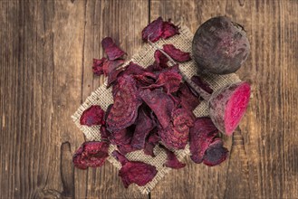 Some fresh Beetroot Chips on wooden background (selective focus, close-up shot)