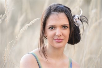 Close-up of a smiling young woman with brown hair in a field of reeds, Bavaria