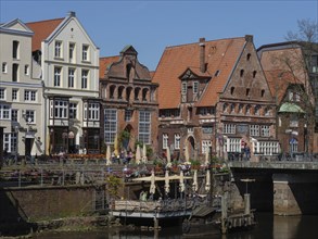 Historic buildings on a canal bank with bridge, lively outdoor area, people are recognisable, some