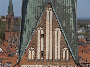 Close-up of a gothic brick church tower with neighbouring town houses, view over an old town with