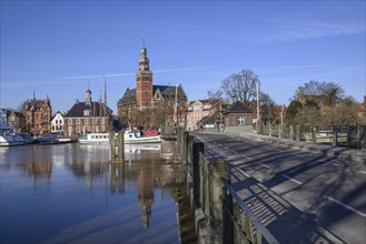 Harbour view with boats on the water, a bridge and historic buildings on the shore under a blue