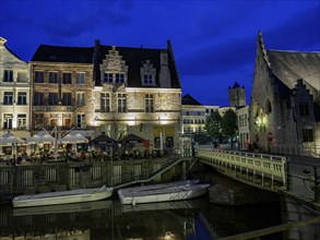Historic buildings and boats on an illuminated canal at dusk, Ghent, Belgium, Europe