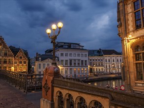 Illuminated canal and historic buildings at night with streetlights, Ghent, Belgium, Europe