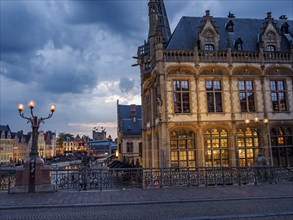 Historic building on a bridge illuminated at dusk, street lights and old town atmosphere, Ghent,