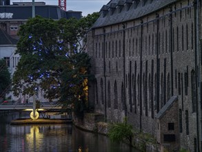 Historic building on the canal bank at dusk, illuminated passages and trees, Ghent, Belgium, Europe