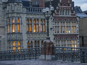 Close-up of historic buildings with illuminated windows and a lantern at dusk, Ghent, Belgium,