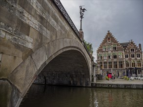 Historic bridge with neighbouring buildings and cloudy sky in the old town, Ghent, Belgium, Europe